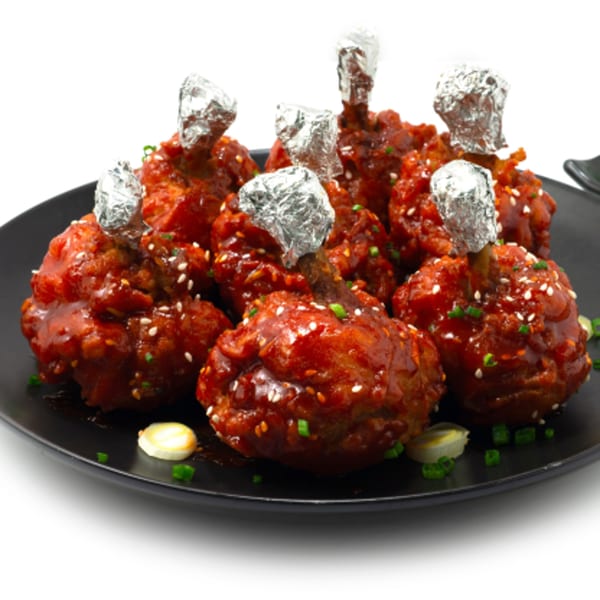 Namaste Express Indian chicken lollipops, glazed in red sauce, topped with sesame seeds and green onions.